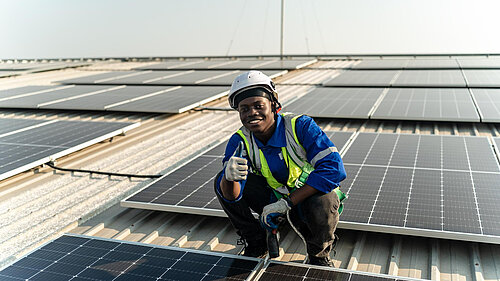 Mid Sussex Times A man putting solar panels on a roof.