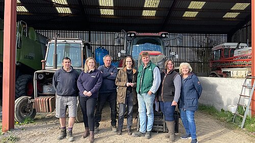 Alison Bennett MP with local farmers in a barn infront of tractors