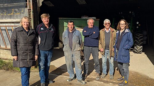 Alison and Local Farmers stood in front of a barn, with some machinery inside