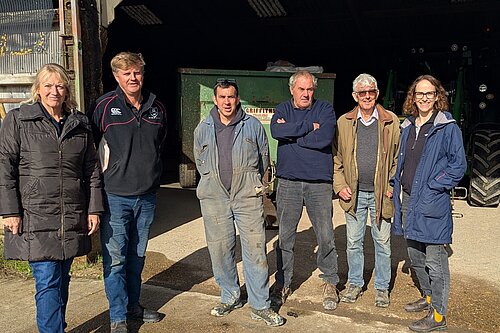 Alison and Local Farmers stood in front of a barn, with some machinery inside