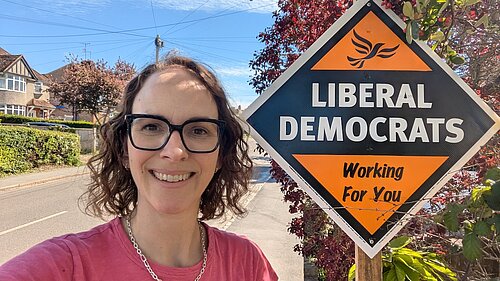 Alison stood next to a Liberal Democrat skateboard in a local village