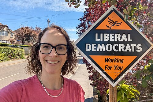 Alison stood next to a Liberal Democrat skateboard in a local village