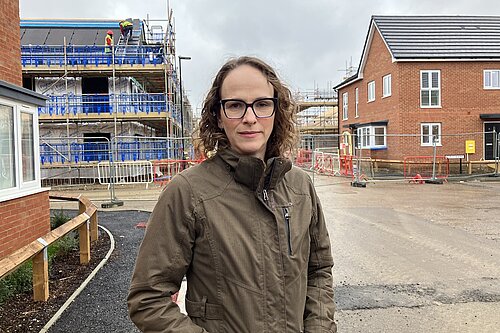 Alison at a building site with half finished houses in background